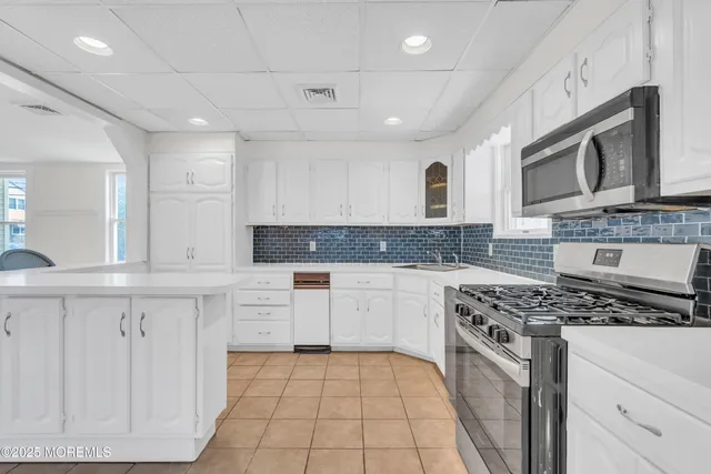 a kitchen with stainless steel appliances granite countertop a stove top oven a sink dishwasher and white cabinets