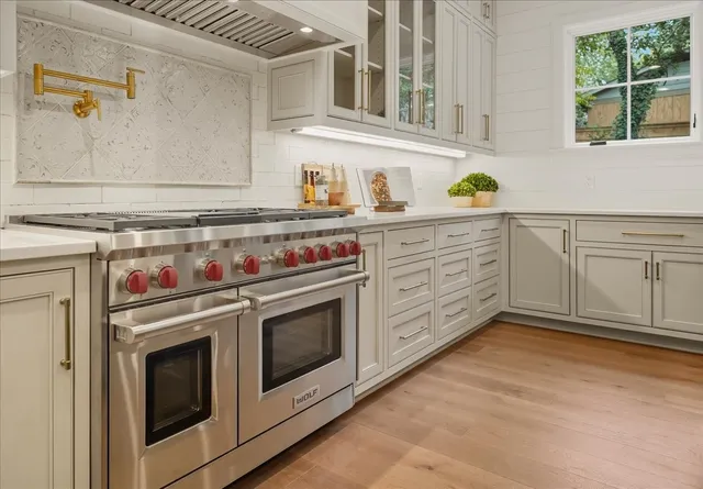 a large white kitchen with a large island oven a stove and a sink