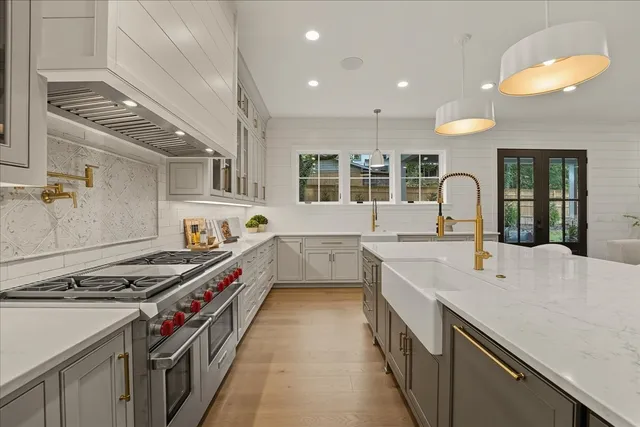 a kitchen with stainless steel appliances granite countertop a sink a stove and a wooden floors