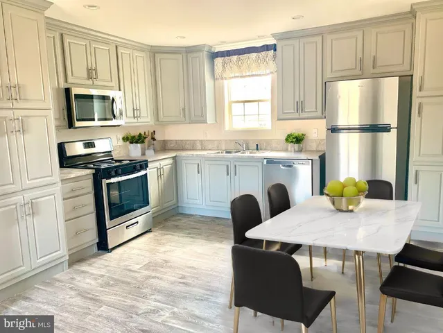 a kitchen with stainless steel appliances granite countertop a stove a refrigerator a microwave a sink and white cabinets