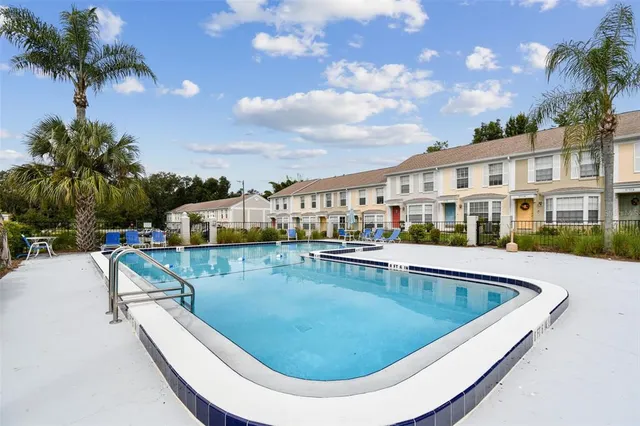 a view of a swimming pool with a lounge chair and palm trees