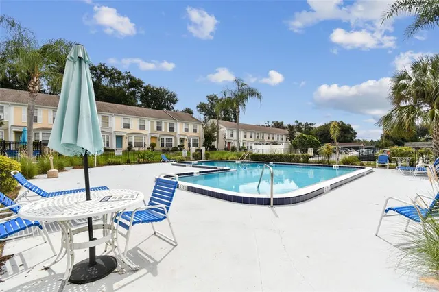 a view of a swimming pool with lawn chairs potted plants and palm tree