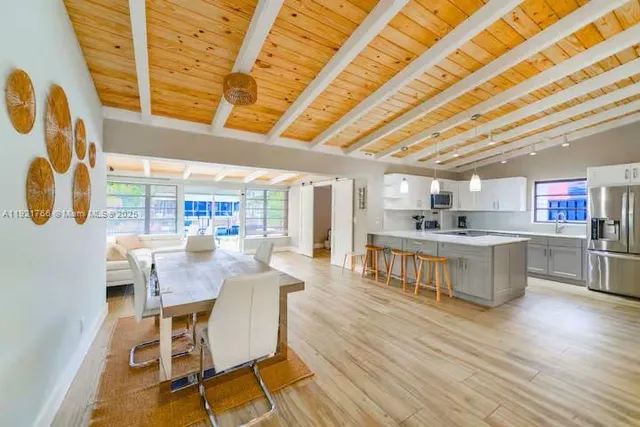 a dining hall with stainless steel appliances wooden floors stove and white cabinets