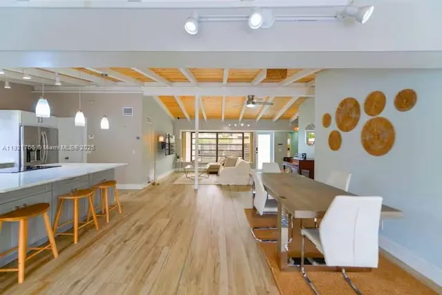 a dining hall with stainless steel appliances a dining table and chairs with wooden floor