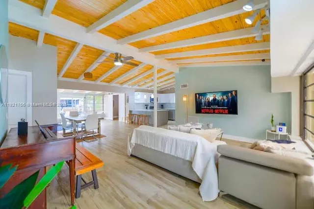 a living room with furniture and a dining table with wooden floor