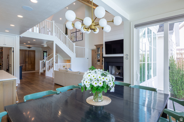 630 East Center Street Alpine, UT 84004 - Photo 29 of 115 Open-concept living area featuring wood-finish flooring, a contemporary chandelier, a two-story staircase with white railings, a fireplace with shiplap detailing, and large glass sliding doors