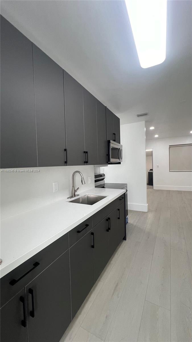 12 Northeast 49th Street, Unit 12 Miami, FL 33137 - Photo 4 of 13 a kitchen with granite countertop a sink white cabinets and stainless steel appliances
