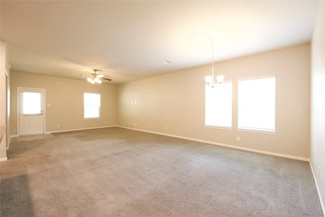 an empty room with windows and chandelier fan