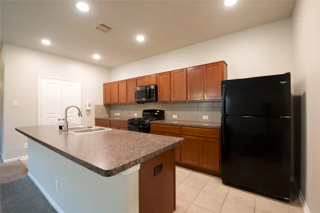 a kitchen with a sink a refrigerator and a stove top oven with wooden floor