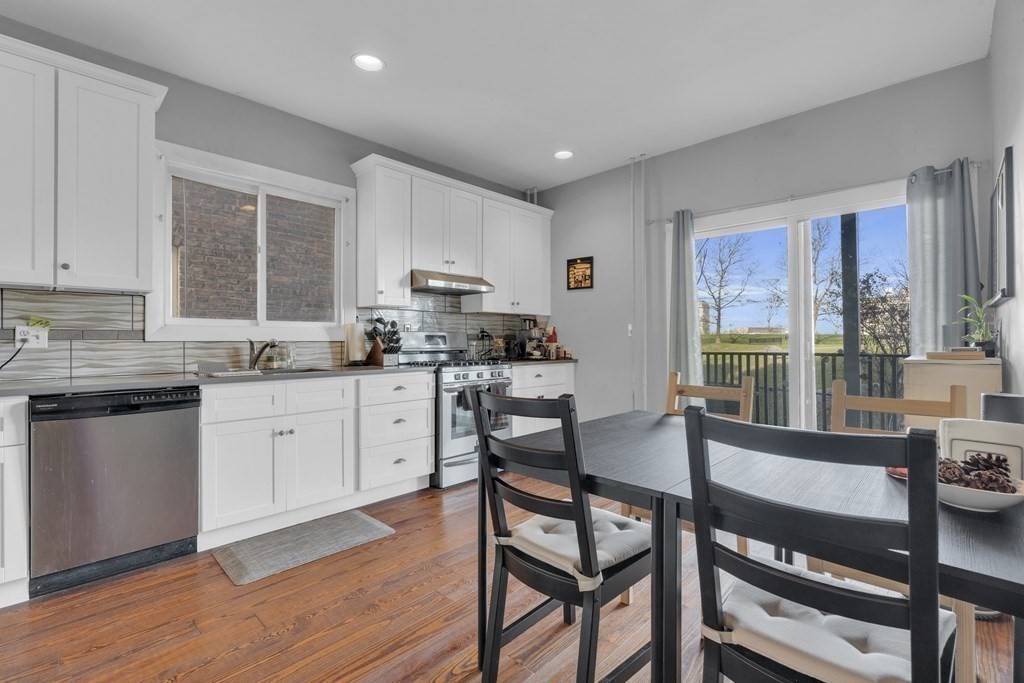 100 Calumet Street Boston, MA 02120 - Photo 4 of 42 a kitchen with stainless steel appliances granite countertop a stove top oven a sink dishwasher a dining table and chairs with wooden floor