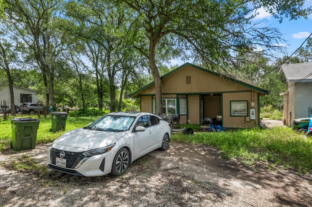 151 High Ridge Drive Del Valle, TX 78617 - Photo 3 of 8 A modest home with natural landscaping offers comfortable living amidst towering trees.