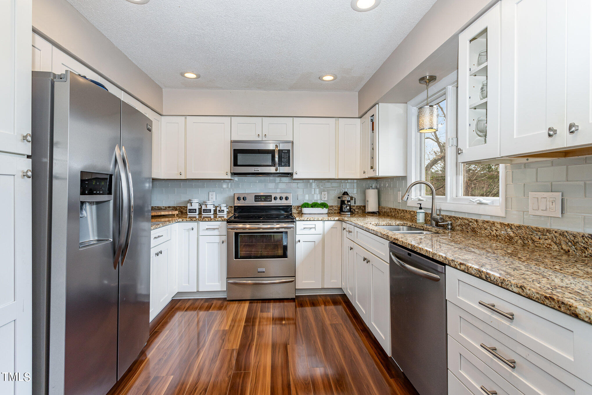 6913 Three Bridges Circle Raleigh, NC 27613 - Photo 12 of 28 a kitchen with kitchen island granite countertop a sink cabinets and stainless steel appliances