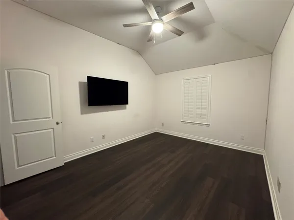 an empty room with wooden floor and fan