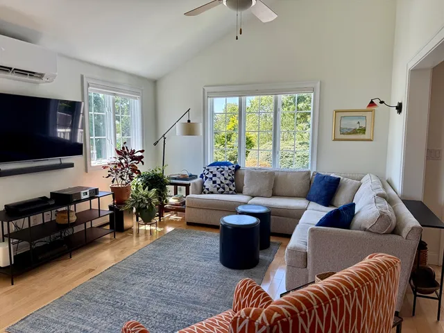 a living room with furniture a flat screen tv and a large window