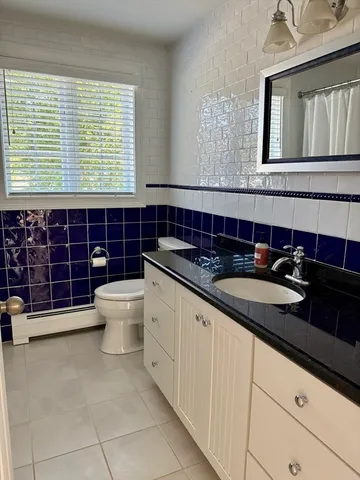 a bathroom with a granite countertop sink a toilet and mirror