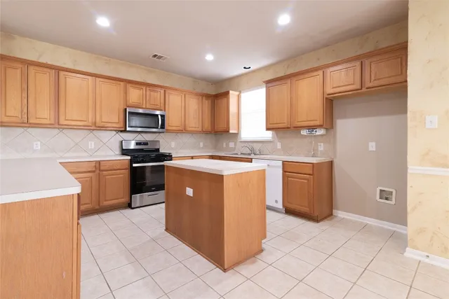 a kitchen with stainless steel appliances granite countertop a stove top oven a sink a refrigerator and white cabinets