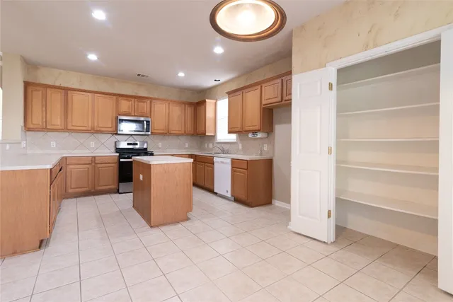 a kitchen with stainless steel appliances granite countertop a stove top oven a sink and a refrigerator