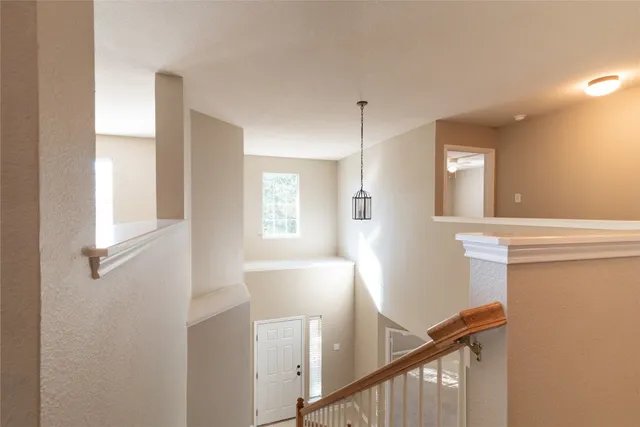 a view of a hallway to a livingroom with wooden floor and a window