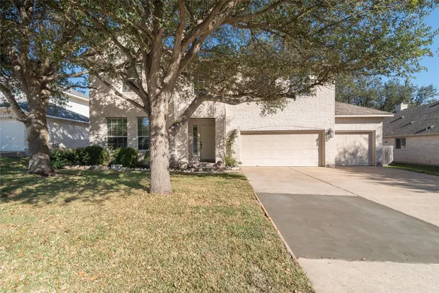 a view of a yard in front of a house with large tree