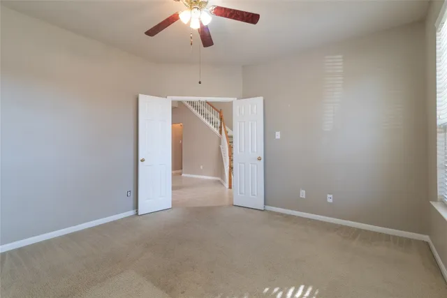 an empty room with chandelier fan and windows