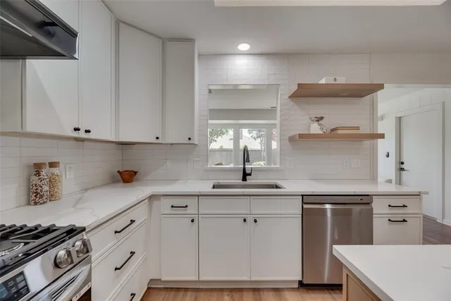 a kitchen with white cabinets and sink