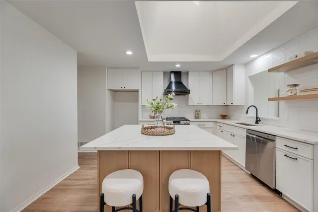 a kitchen with stainless steel appliances granite countertop a sink a stove a kitchen island with chairs and white cabinets