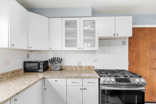 a kitchen with granite countertop white cabinets and stainless steel appliances