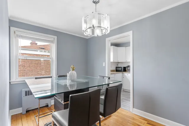 a dining room with wooden floor a chandelier a wooden table and chairs