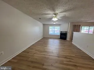 an empty room with wooden floor fan and windows