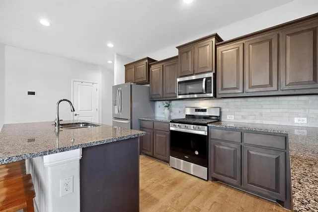 a kitchen with stainless steel appliances granite countertop a sink stove and refrigerator