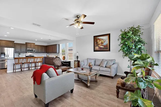 a living room with furniture flowers and a kitchen view