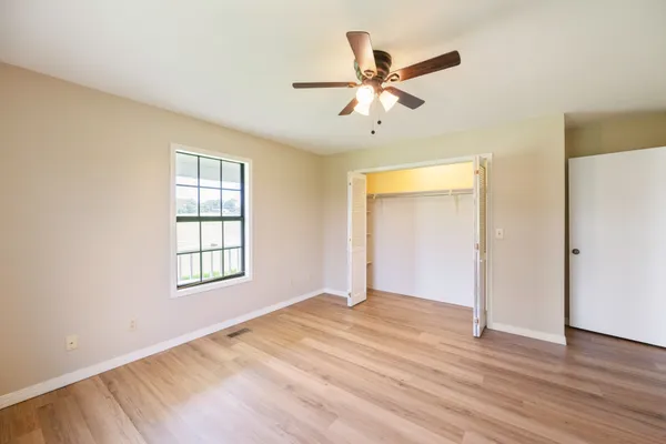 a view of an empty room with wooden floor and a window