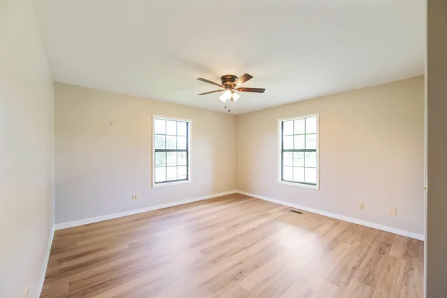 an empty room with wooden floor and windows