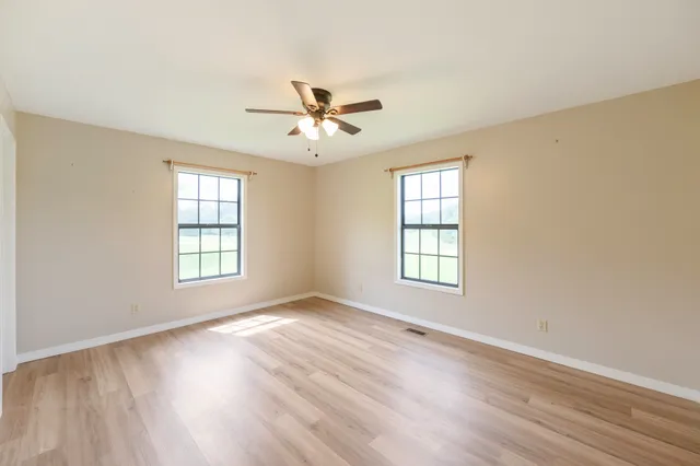 a view of an empty room with a window and wooden floor