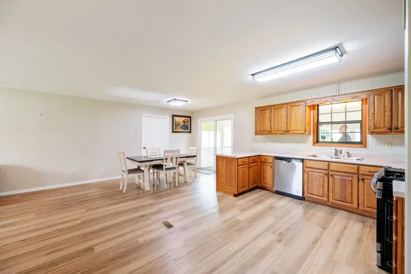 a large kitchen with granite countertop a stove a sink a dining table and chairs with wooden floor