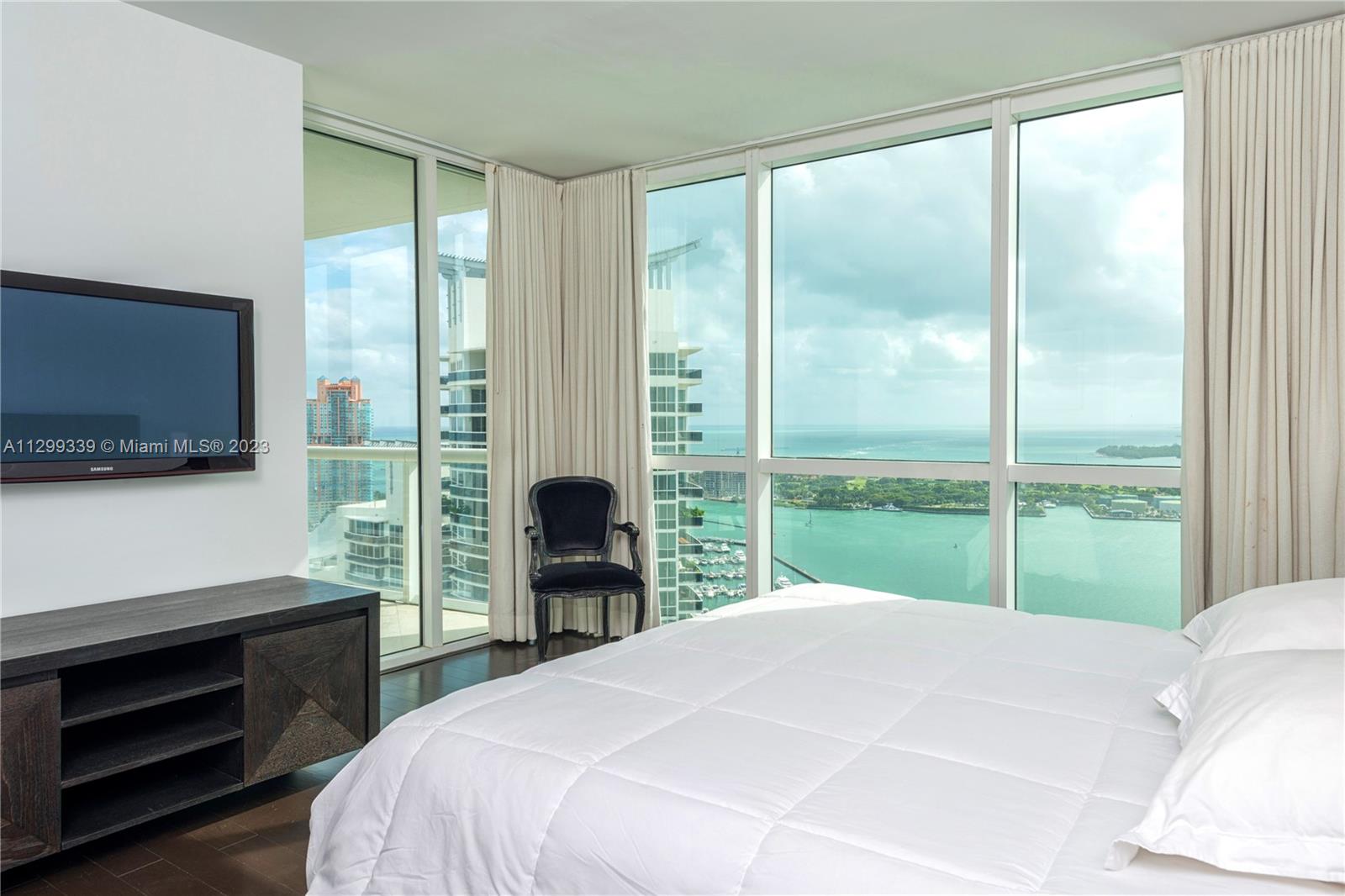 450 Alton Road, Unit 3603 Miami Beach, FL 33139 - Photo 18 of 25 a bedroom with a bed and a flat tv screen next to a window