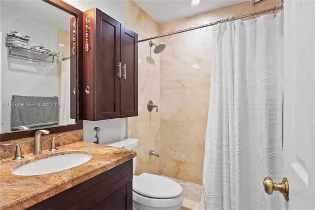 a bathroom with a granite countertop sink toilet and shower
