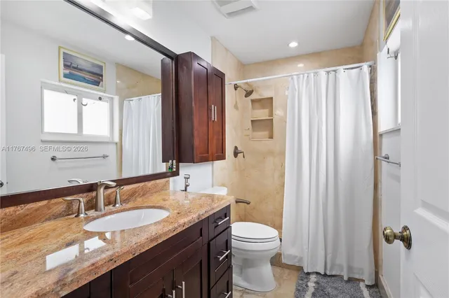 a bathroom with a granite countertop sink toilet and shower