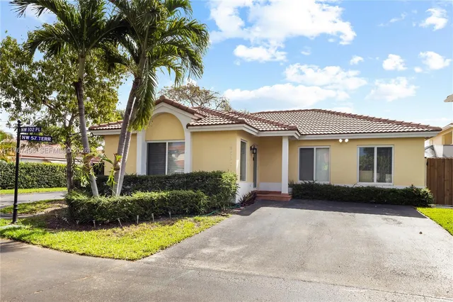 a front view of a house with a garden and trees