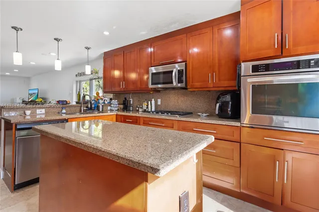 a kitchen with stainless steel appliances granite countertop a sink a stove counter space and cabinets