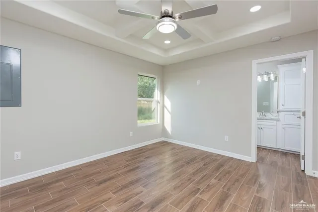 an empty room with wooden floor a ceiling fan and windows