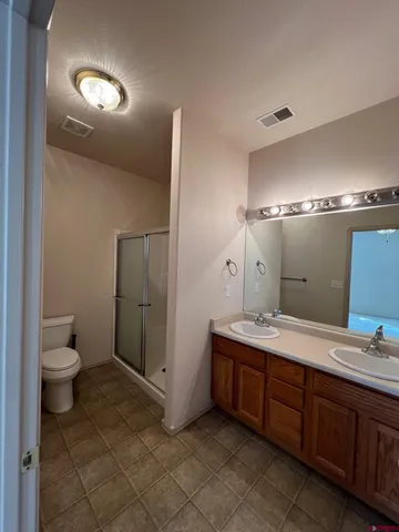 a spacious bathroom with a double vanity sink a toilet and a mirror
