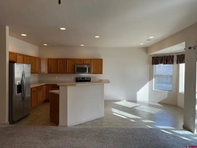a kitchen with stainless steel appliances kitchen island granite countertop a refrigerator a stove and a sink