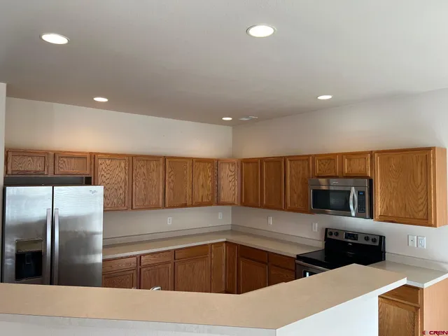 a kitchen with granite countertop a refrigerator and a stove top oven