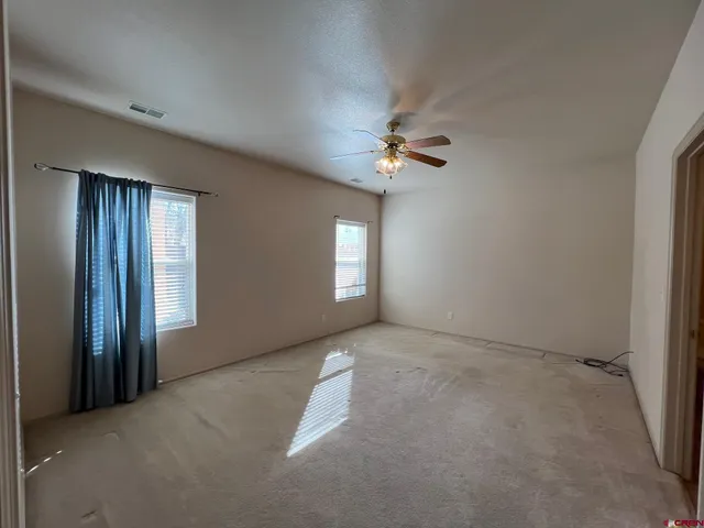 an empty room with windows and chandelier fan