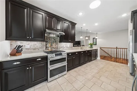 a kitchen with stainless steel appliances granite countertop a sink stove and cabinets