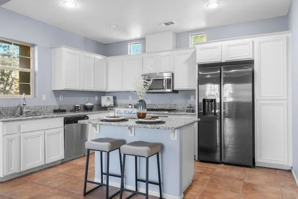a kitchen with a sink a refrigerator and white cabinets