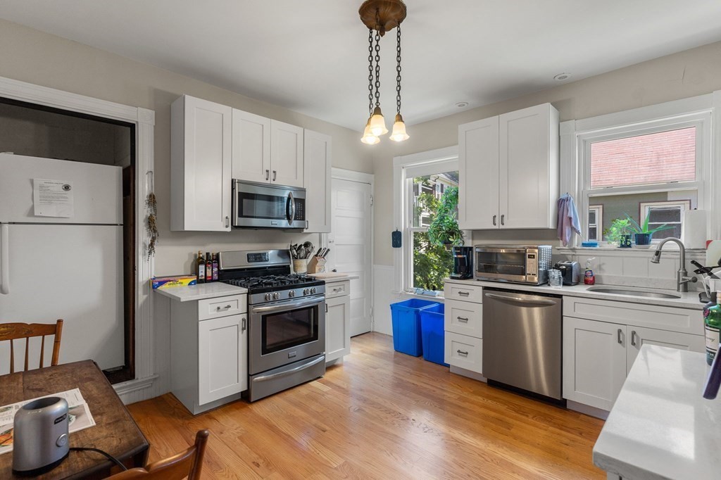 10-12 Castlerock Street, Unit 2 Boston, MA 02125 - Photo 7 of 24 a kitchen with stainless steel appliances granite countertop a sink a stove a refrigerator cabinets and a dining table with wooden floor