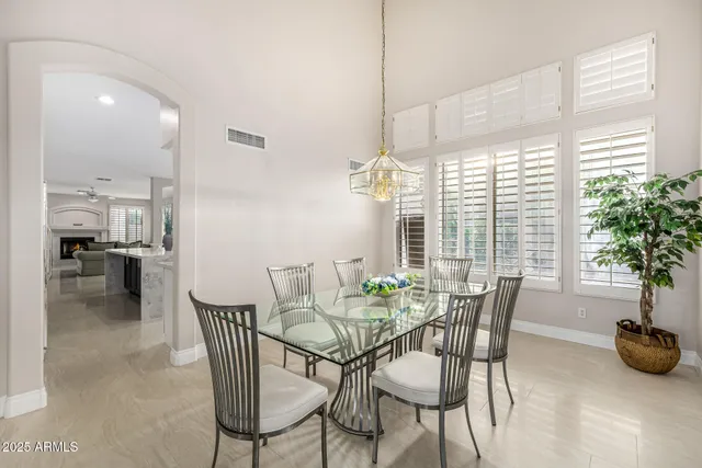 an empty room with wooden floor chandelier fan and windows