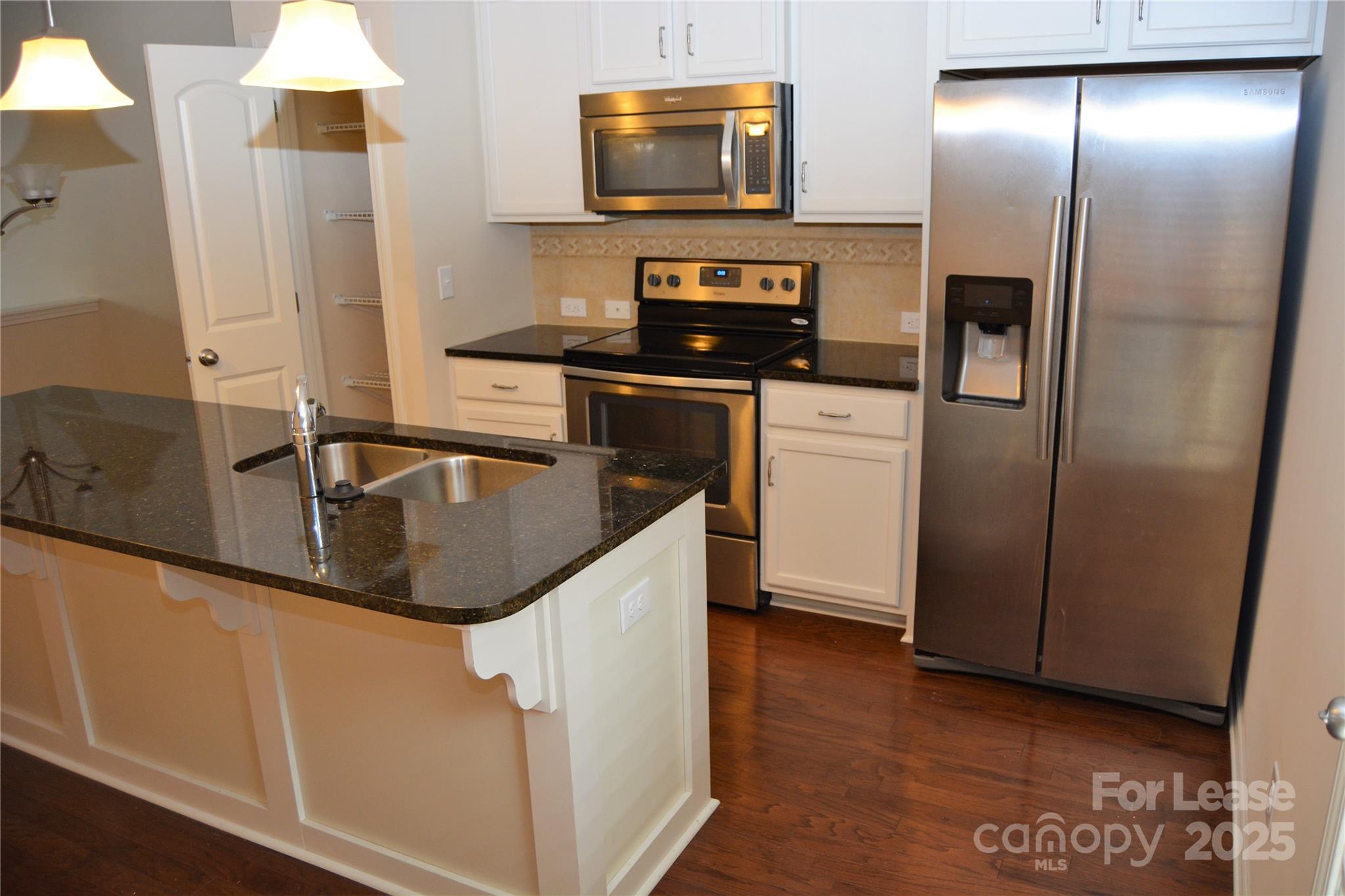 5212 Prosperity Church Road Charlotte, NC 28269 - Photo 2 of 5 a kitchen with stainless steel appliances granite countertop a refrigerator a stove and a sink with wooden floor